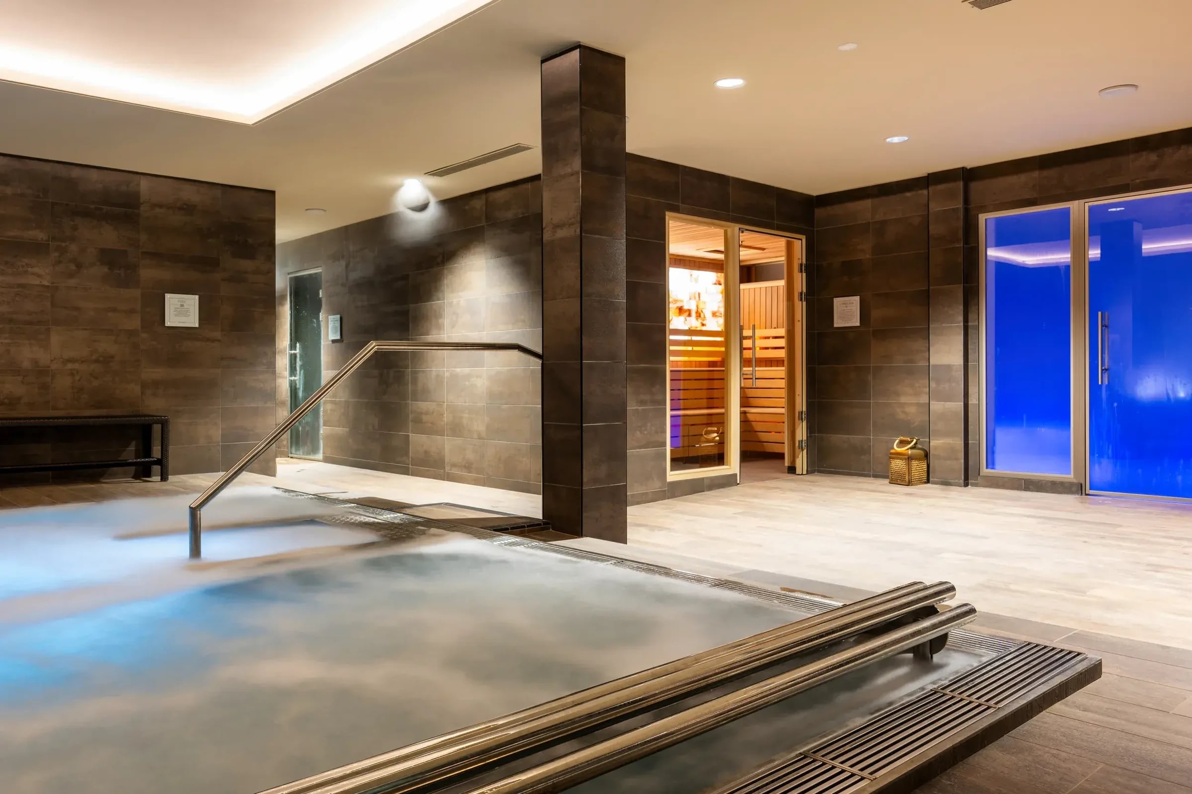 Spa des David Lloyd Country Club Geneva mit dampfendem Hydropool, Salzsauna und blau beleuchteter Glastür